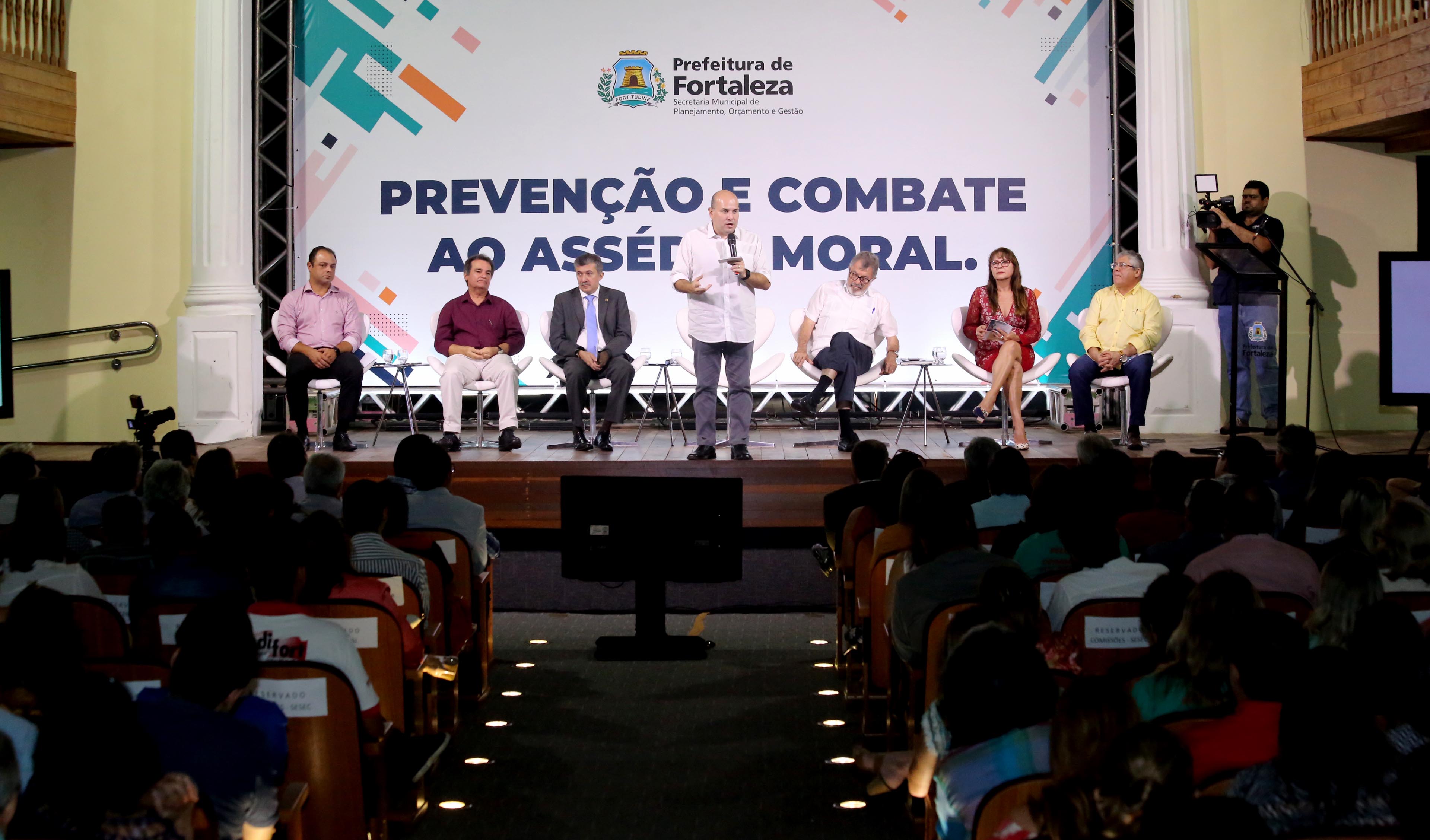 foto mostra o palco do teatro são josé com um grupo de pessoas sentadas em cadeitas